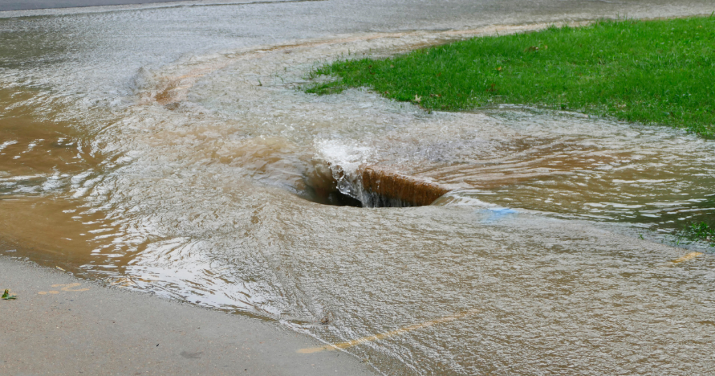 Sewer drain is overwhelmed with water; street flooding.