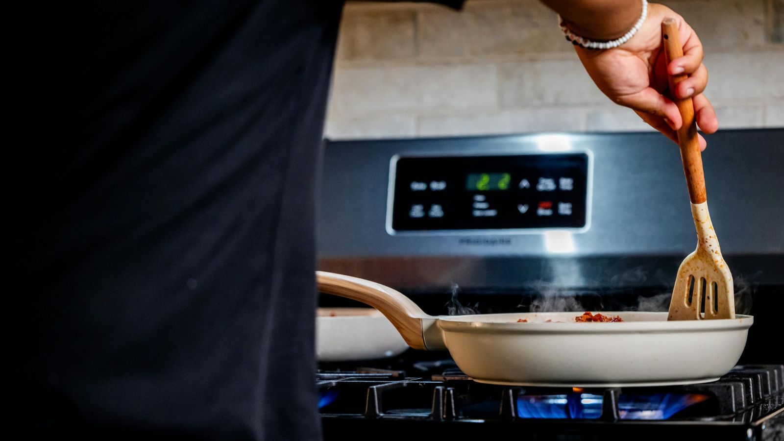 Person cooks food in a sauce pan over a gas stove.