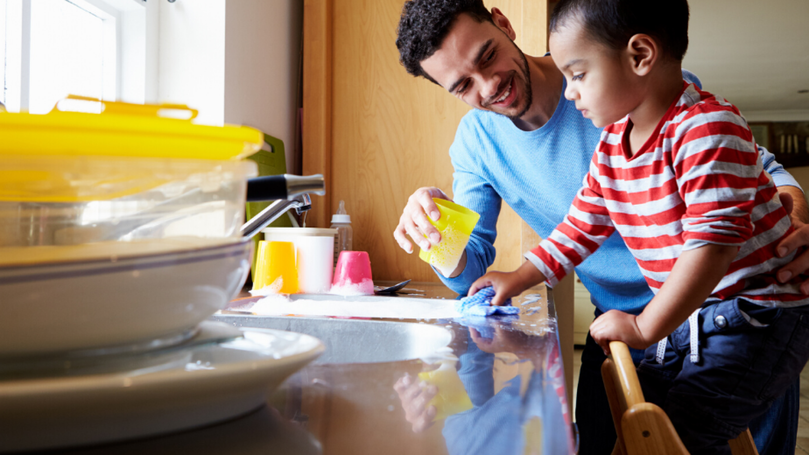 father helps son at kitchen sink